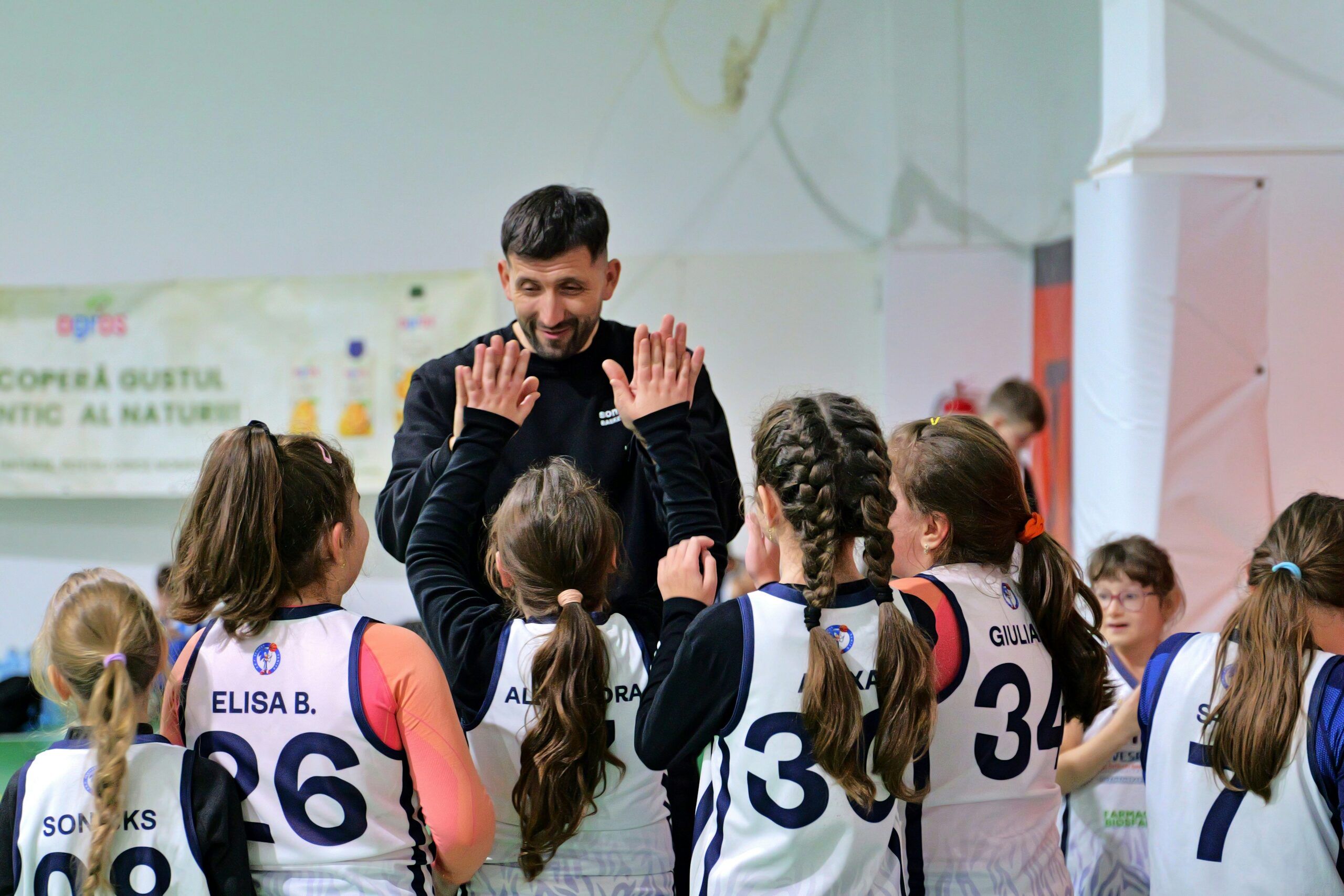 Allenatore di basket che interagisce con una squadra di bambine durante un allenamento